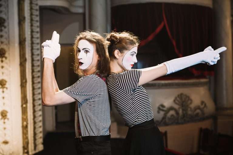 male mime female mime standing back back making hand gun gesture